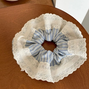Macro shot of blue striped scrunchie with detailed white lace trim on wooden background