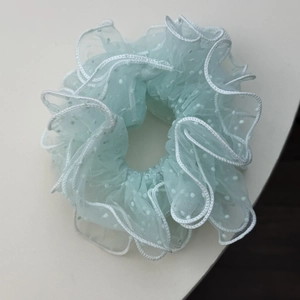 Detail of light mint green mesh scrunchie with white polka dots and ruffled edges