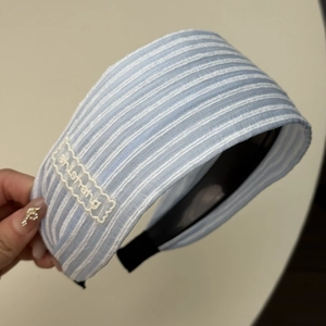 Gros plan d'un serre-tête rayé bleu avec broderie blanche et embouts de protection noirs