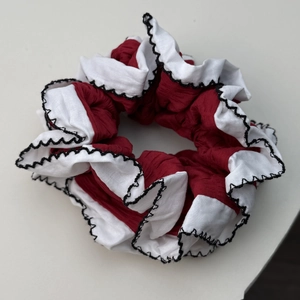 Détail de chouchou plissé rouge et blanc avec bords ondulés noirs pour coiffure femme