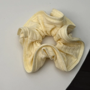 Détail du tissu en maille côtelée jaune clair sur un chouchou montrant la texture douce