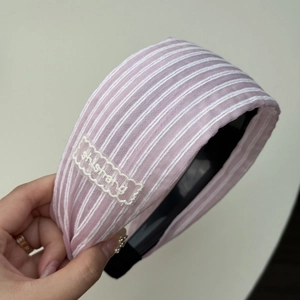 Détail d'un bandeau à rayures roses avec broderie ondulée blanche et logo shishang