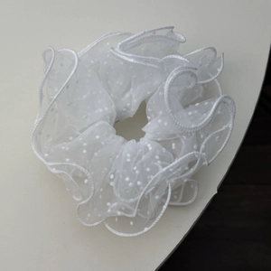 Close-up of white mesh lace scrunchie featuring elegant polka dots and fine stitching