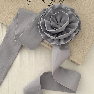 Chouchou fleur rose 3D grise faite main avec de longs rubans sur fond beige texturé