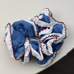 Détail du chouchou plissé bleu et blanc avec coutures ondulées rouges et texture