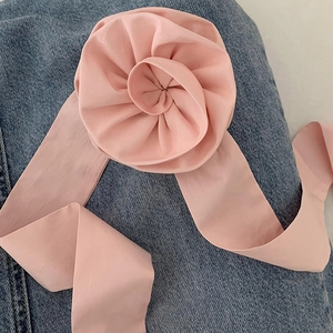 Détail macro d'un chouchou rose en tissu 3D avec ruban long sur un fond en tissu denim