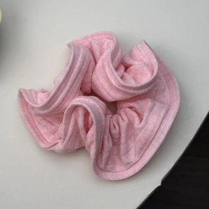 Détail de la texture d'un chouchou en maille rayée rose avec bords volantés
