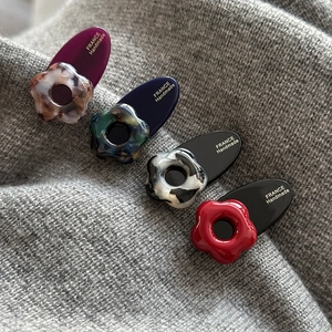 Lot de quatre barrettes à fleurs en résine bordeaux, bleu et noir sur fond en tricot fin