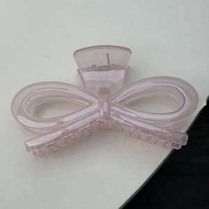 Macro view of a pink translucent jelly hair claw clip with a hollow bow design