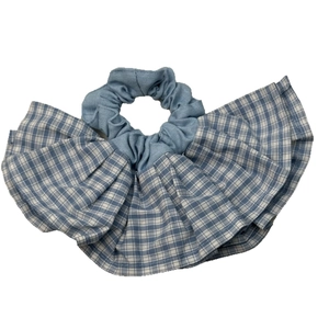 Chouchou géant à carreaux bleus avec volants et design multicouche sur fond blanc épuré