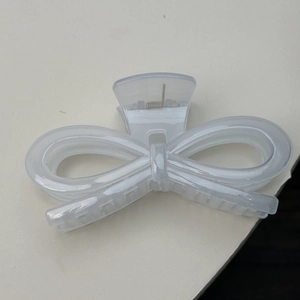 Detail shot of a translucent white jelly bow hair claw clip with its metal spring