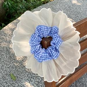 Close-up of blue plaid scrunchie with sheer organza ruffles on a wooden chair