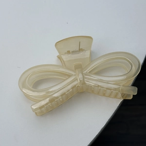 Close-up of translucent cream resin hair claw clip with a hollow bow knot design