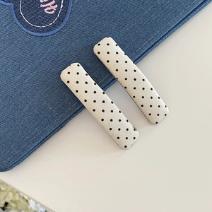 Dettaglio di fermagli per capelli in tessuto bianco a pois neri su sfondo in denim