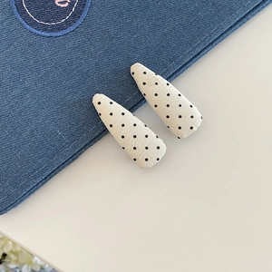 Dettaglio di fermagli per capelli in tessuto con pois neri classici su base beige