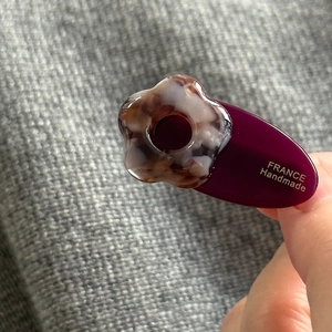 Détail de la pince à cheveux ovale violette avec fleur en écaille et texte doré