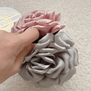 Détail de pinces à cheveux roses et grises en satin avec des pétales de rose soyeux