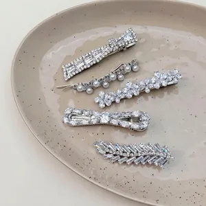 Elegant 5-piece silver hair clip set with sparkling crystals and pearls on a ceramic plate