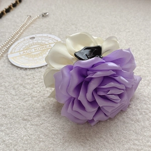 Vue rapprochée d'une pince à cheveux rose en satin violet et beige sur peluche