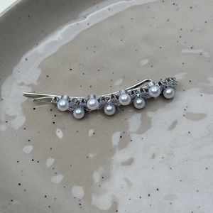 Detail view of a silver hair clip featuring white imitation pearls and clear cubic zirconia