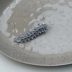 Detailed macro view of crystal-encrusted leaf hair clip on elegant ceramic dish