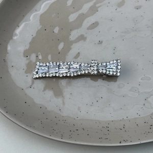Detailed view of rectangle hair clip with crystals on a grey ceramic plate