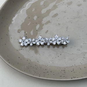 Macro shot of sparkling silver flower hair clip with zirconia stones on a ceramic tray