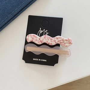 Détail de barrettes à cheveux ondulées en acétate fleuri et rose sur carte de support
