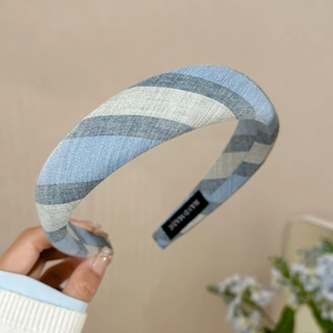 Détail d'un serre-tête en tissu à rayures bleues et blanches avec étiquette fait main