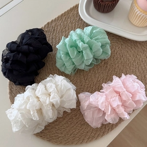 Pastel cloud puff hair scrunchies in mint green, pink, and white on a woven mat