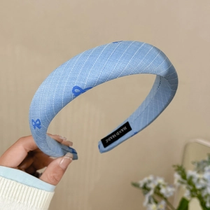 Détail du serre-tête bleu rayé avec étiquette 'HAND MADE' et motif de nœuds