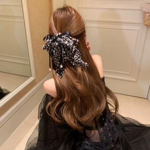 Pince à cheveux fleurie avec rubans noirs et pendentif perle sur cheveux bruns ondulés