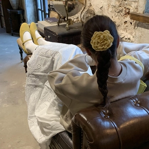Handmade yellow plaid flower hair clip worn on a braided hairstyle in a retro room