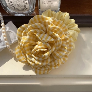 Detailed view of yellow and white checkered floral hair claw with fabric petal texture