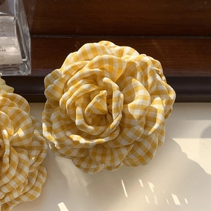 Detailed macro view of yellow and white plaid fabric rose petals on the hair claw clip
