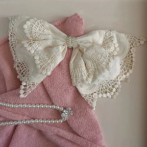 Elegant French style cream lace bow hair clip with central pearl on pink knit background