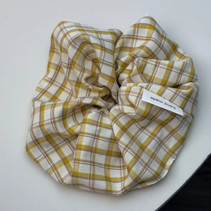 Détail du chouchou à carreaux jaunes avec étiquette faite main et texture du tissu