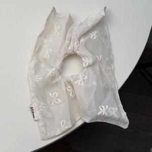 Détail d'un chouchou géant en résille blanche avec broderie nœud et étiquette tissée fine