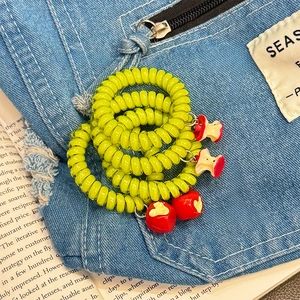 Neon green spiral apple charm hair ties for ponytails set of four on denim fabric