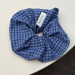 Detail of blue and white checkered fabric scrunchie with a sewn handmade label