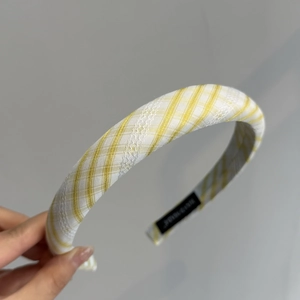 Détail d'un serre-tête à carreaux jaunes avec dentelle blanche et étiquette noire