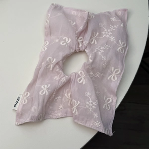 Détail du chouchou en maille rose avec broderie blanche de nœuds et fleurs sur tissu
