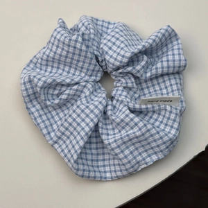 Detailed view of blue and white checkered scrunchie with a handmade woven label
