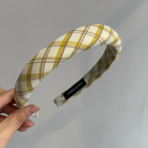 Détail macro du chouchou à carreaux jaunes avec une étiquette noire cousue Hand Made