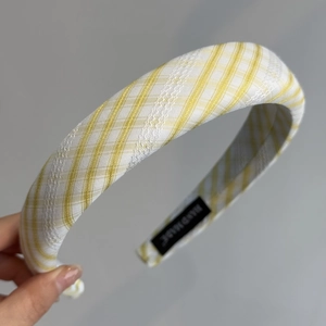 Détail d'un serre-tête à carreaux jaunes avec dentelle blanche et étiquette faite main