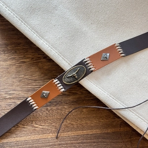 Detailed macro view of stitched leather belt with vintage bull head metal buckle design