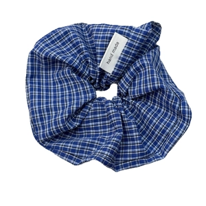 Blue and white checkered fabric scrunchie with a handmade label on a white background