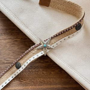 Detailed close-up of bohemian woven belt with turquoise star metal buckle and silver rivets