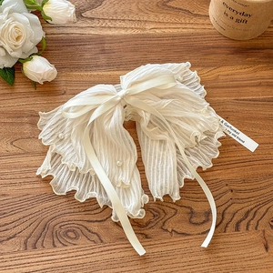 Elegant cream white chiffon bow hair scrunchie with pearls on a rustic wood background