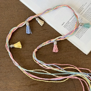 Close-up of bohemian colorful braided hairband with pastel tassels and metal beads